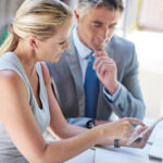 Deux professionnels vérifient ensemble des informations sur une tablette.