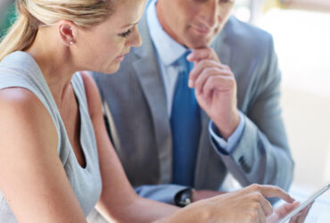 Deux professionnels vérifient ensemble des informations sur une tablette.