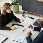 Deux personnes examinent des documents financiers autour d’une table